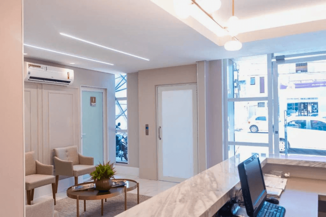 Entrada principal e sala de espera do escritório, com decoração clean e ambiente climatizado.